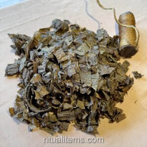 A pile of loose Mapacho leaf pieces beside a short, bound roll on a table.