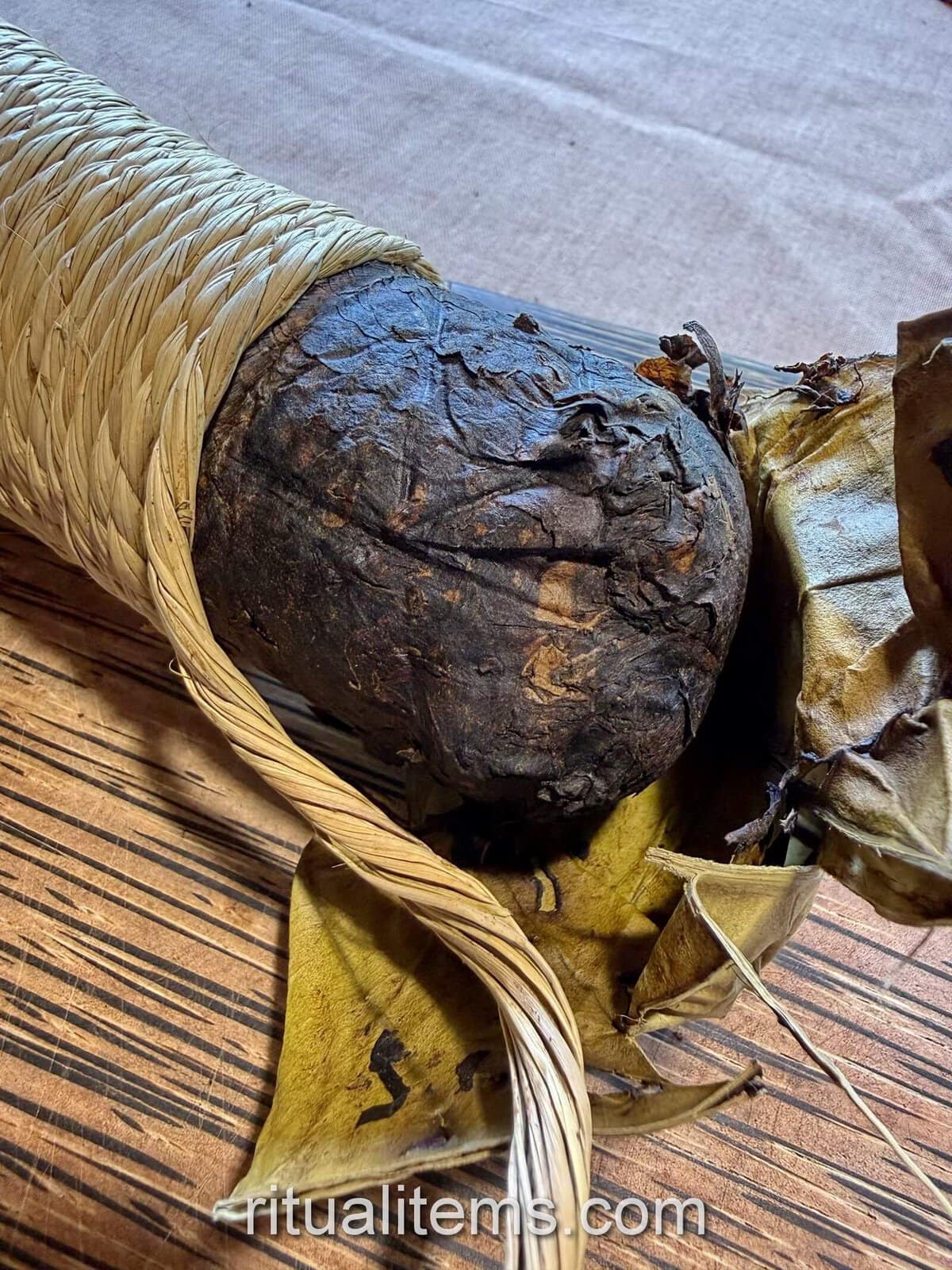 A Mapacho roll with the end wrapping peeled back to expose the rounded leaf bundle.
